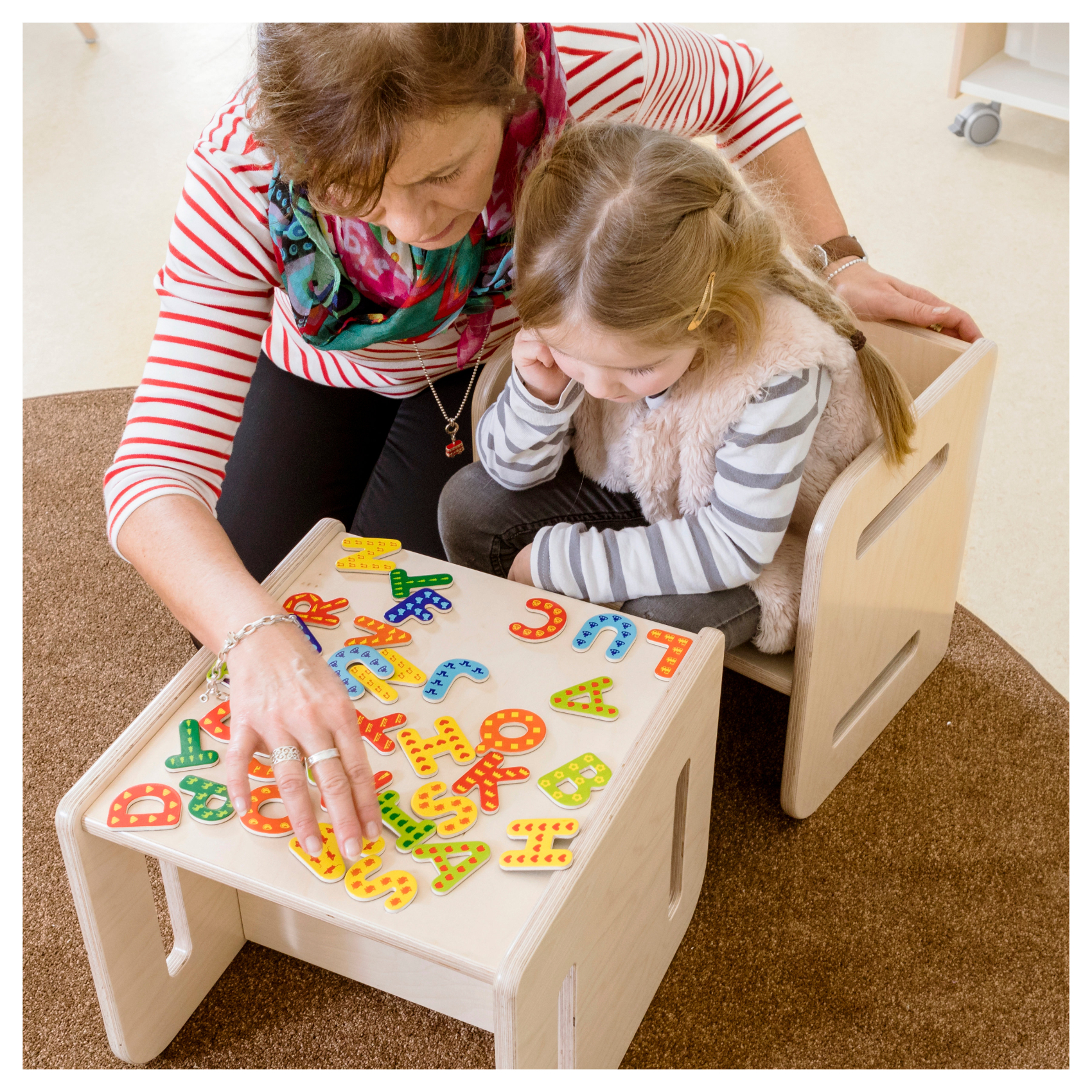 Mädchen und Erzieherin spielen in Kita